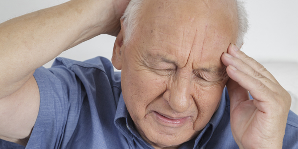photograph of an elderly man holding his head due to a brain tumour induced headache