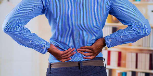 photograph of man holding his low back due to pain from degenerative disc disease